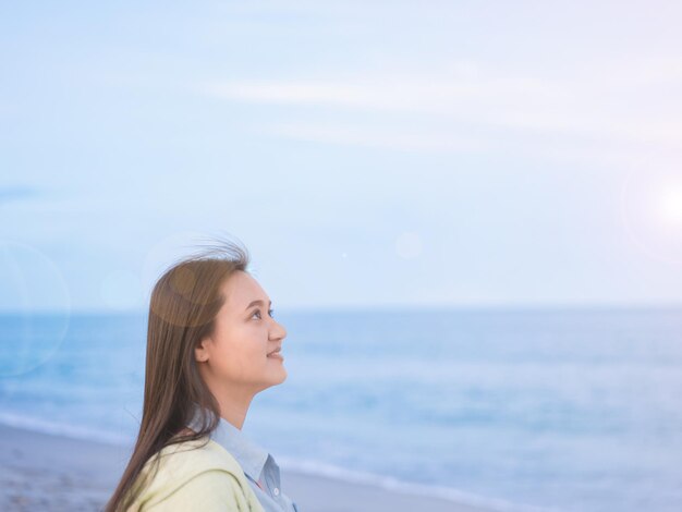 Foto tire um tiro na cabeça de uma mulher asiática caminhando pelo mar ao longo da praia olhando para o céu livre