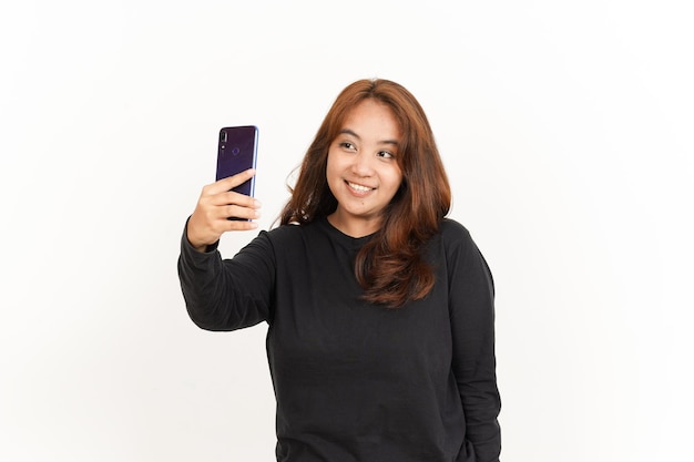 Tire uma selfie usando o smartphone de uma linda mulher asiática vestindo camisa preta isolada em branco