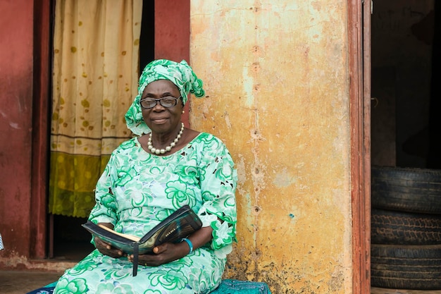 Tiro aberto de mulher africana sênior negra sentada segurando um livro na mão