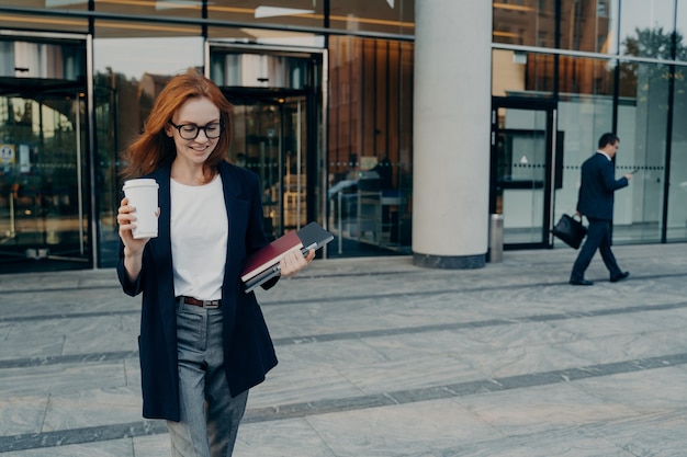 Foto tiro al aire libre de la empresaria lleva portátil tableta digital para escribir notas de café