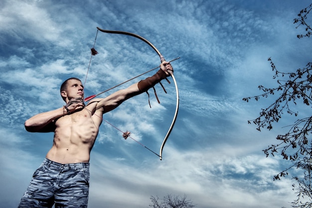 Foto tiro al arco. joven arquero entrenando con el arco.