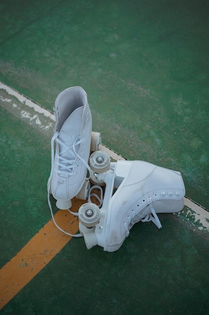 Tiro de ángulo alto de un par de patines blancos junto con cordones desatados en una cancha verde