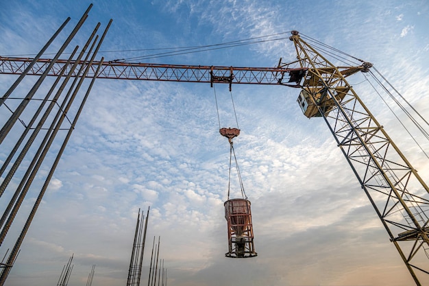 Un tiro de ángulo bajo de una grúa con equipo en un sitio de construcción cerca de una nueva infraestructura de construcción