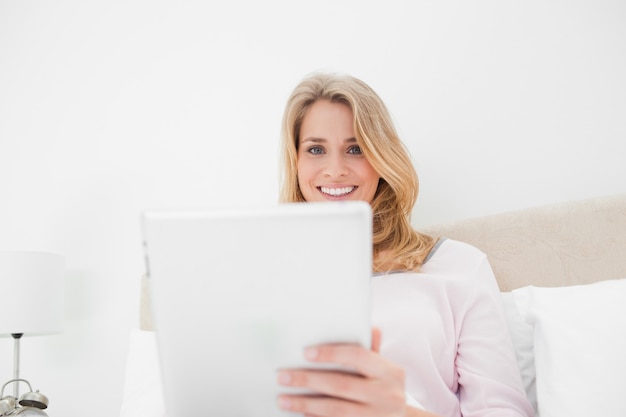 Tiro de ángulo bajo, mujer con tablet pc mientras sonriendo y mirando hacia adelante