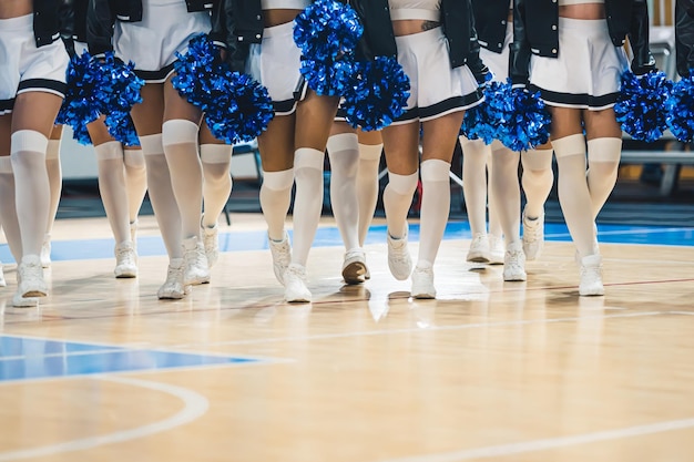 Tiro de ángulo bajo de mujeres jóvenes porristas caminando hacia la cámara en una cancha de baloncesto