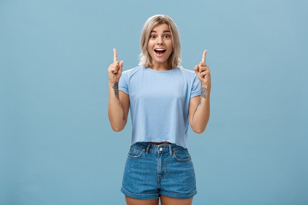 Tiro de cintura para arriba de mujer rubia creativa entusiasta impresionado en traje de verano de moda sonriendo jadeando