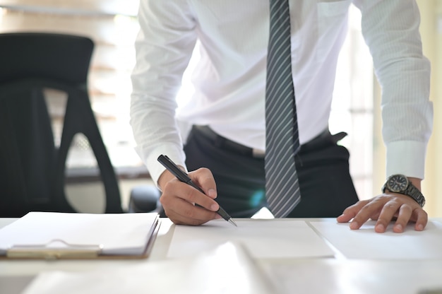 Tiro colhido do contrato de assinatura do homem de negócios que faz um acordo no local de trabalho do escritório.