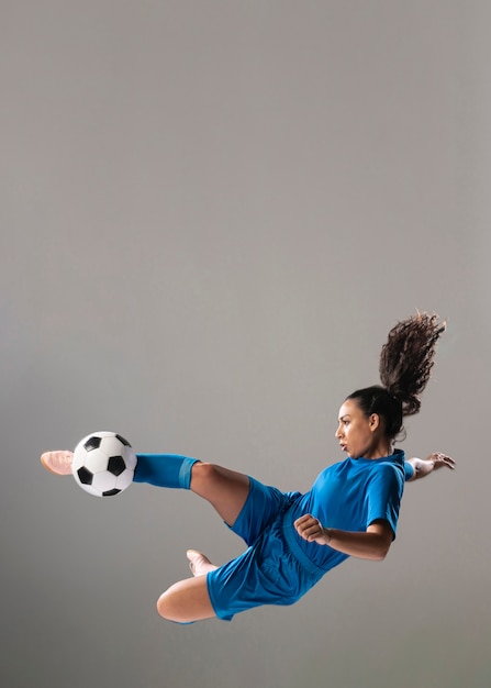 Foto tiro completo, atlético, mulher, chutando bola