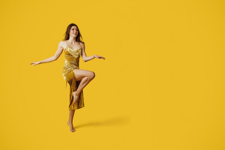 Foto tiro completo da senhora elegante em vestido dourado elegante posando no fundo do estúdio amarelo grátis