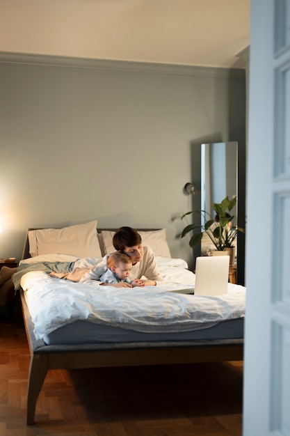 Foto tiro completo de mulher deitada na cama com um bebê