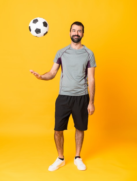 Tiro completo de um homem de jogador de futebol sobre fundo amarelo isolado