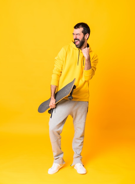 Tiro completo do homem sobre amarelo isolado com um skate