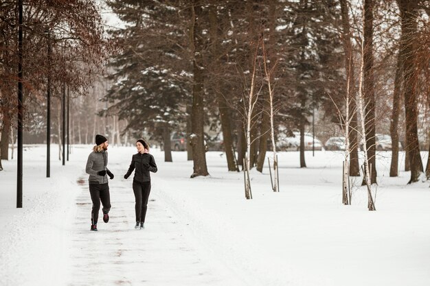 Tiro completo hombre y mujer corriendo en el bosque