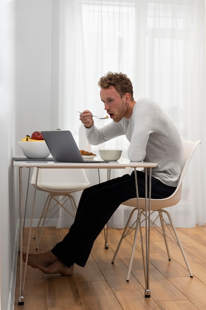 Foto tiro completo homem comendo na mesa