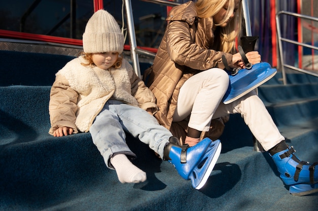 Foto tiro completo mãe e menina colocando patins