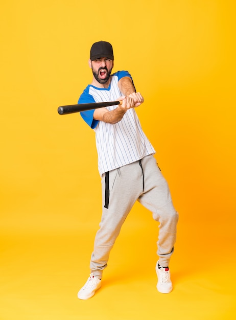 Foto tiro de cuerpo entero de un hombre jugando béisbol sobre amarillo aislado