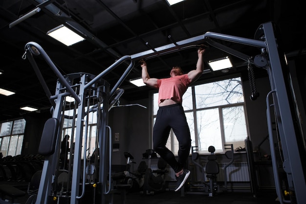 Tiro de ângulo baixo de um esportista fazendo pullups no ginásio