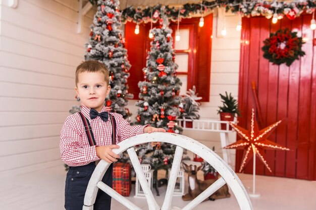 Tiro de ano novo da família no estúdio Pai segura sua filha nos braços uma garota pendura uma bola de Natal em uma árvore de Natal