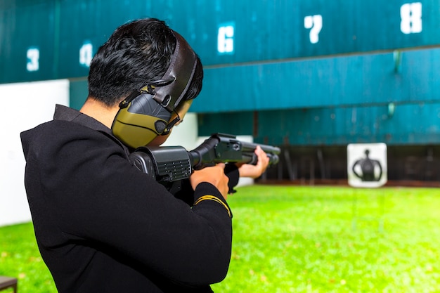 Tiro de arma por duas mãos no campo de tiro da academia.