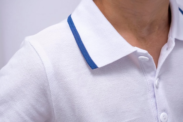 Tiro de close-up com um menino no pólo branco com um fragmento de faixa azul da foto da criança de terno em um fundo branco isolado publicidade de roupas da moda para meninos em uniformes escolares