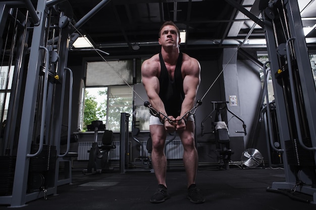 Tiro de corpo inteiro de um esportista musculoso fazendo exercícios de músculos do peito no ginásio