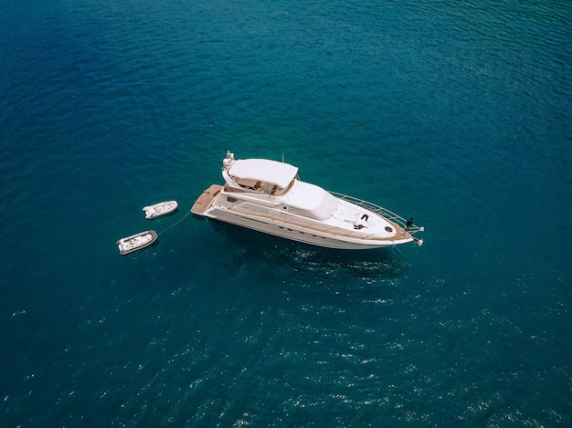 Tiro de drone do belo iate branco no mar azul quente; conceito de riqueza.