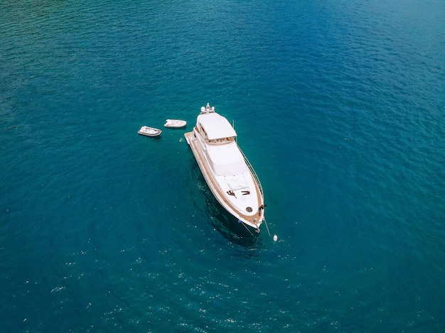 Tiro de drone do belo iate branco no mar azul quente; conceito de riqueza.