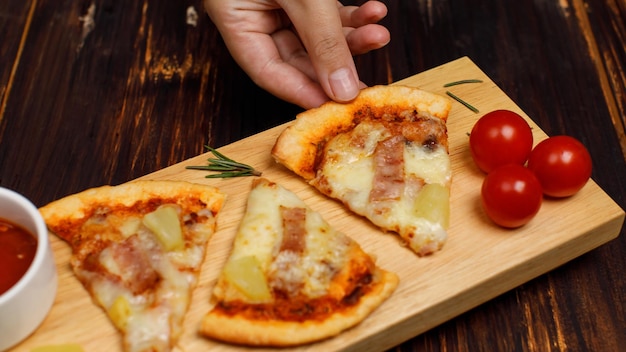 Tiro de estúdio de vista superior closeup de três pedaços de forno quente assado saboroso delicioso presunto caseiro italiano e abacaxi Pizza de massa de pão macio havaiana decorada na panela de madeira com ketchup de tomate