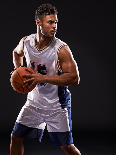 Foto tiro de estúdio do jogo de um jogador de basquete contra um fundo preto