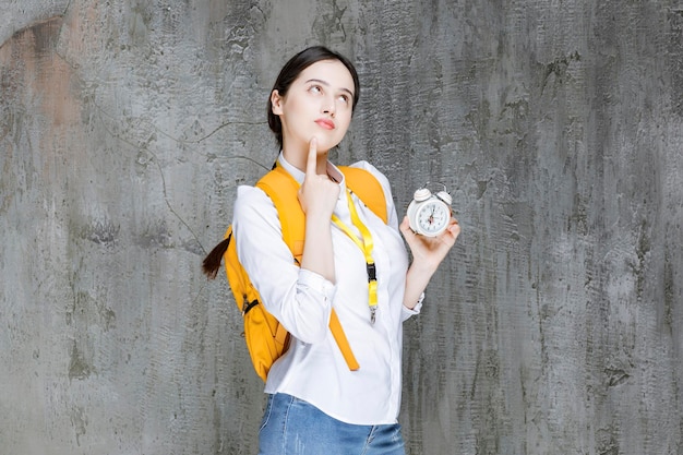 Tiro de jovem estudante com mochila mostrando o tempo no relógio. Foto de alta qualidade