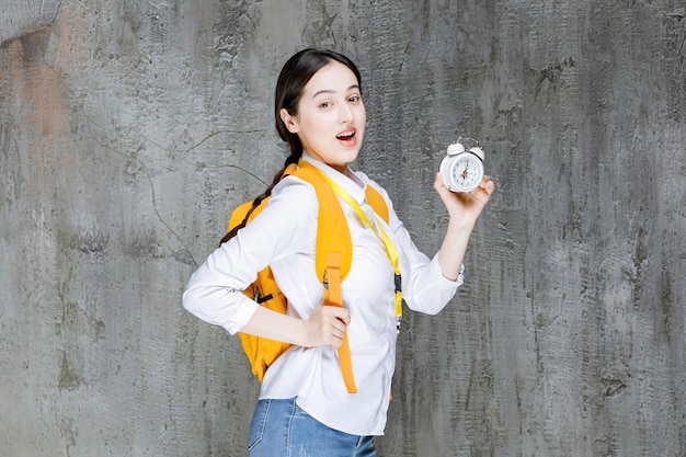 Tiro de jovem estudante com mochila mostrando o tempo no relógio. Foto de alta qualidade