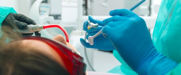 Foto tiro de tamanho de banner de um paciente e mãos de dentista em luvas prontas para limpar os dentes