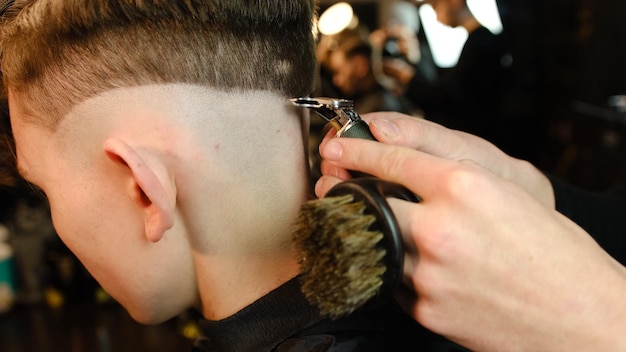 Tiro de um barbeiro bonito dando um corte de cabelo para seu cliente usando aparador Serviço de cabeleireiro em uma barbearia moderna em um raio de chave escura com vista lateral de luz quente