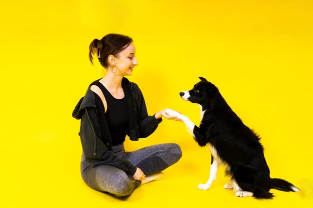 Tiro de uma fêmea esportiva em perneiras com um cachorro border collie isolado em fundo amarelo e vermelho