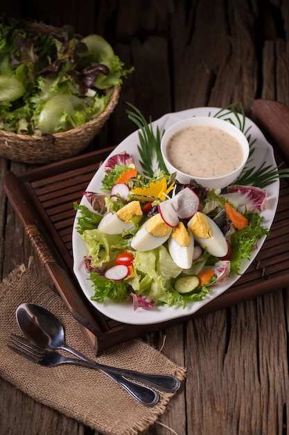 Tiro de ensalada verde con rábano y huevo duro en plato blanco con tenedor y servilleta