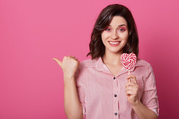 Tiro horizontal de atractiva mujer sonriente con expresión complacida