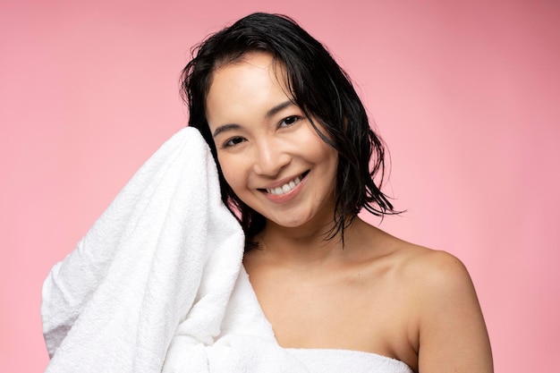 Tiro horizontal de atraente mulher limpa o cabelo molhado com toalha