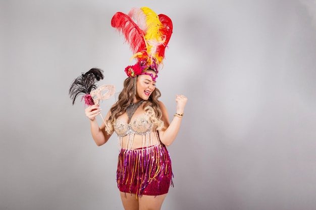 Tiro horizontal de meio corpo linda mulher brasileira em roupas de carnaval segurando máscara de carnaval