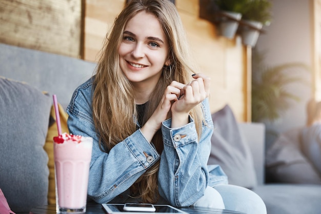 Tiro horizontal de namorada europeia amigável em jeans elegante