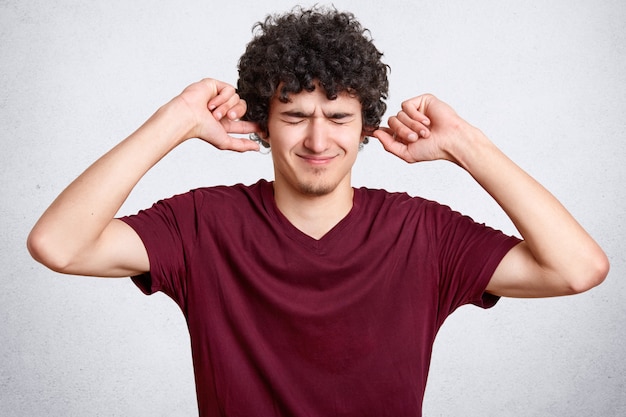 Tiro horizontal do homem descontente tem cabelo encaracolado