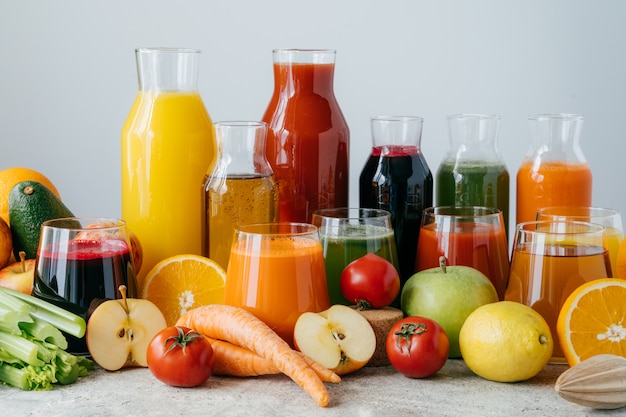 Tiro horizontal de verduras y frutas exprimidas en botellas de vidrio.