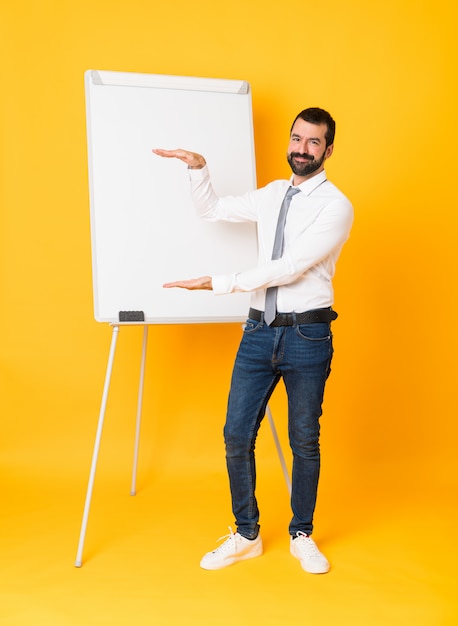 Tiro integral del empresario dando una presentación en el pizarrón sobre copyspace amarillo aislado para insertar un anuncio