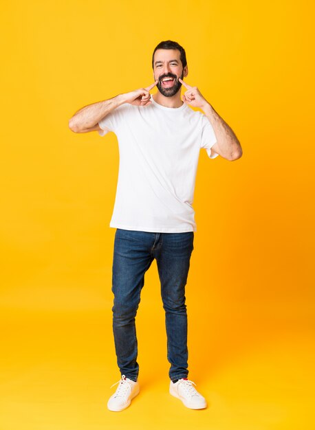 Tiro integral del hombre con barba sobre amarillo aislado sonriendo con una expresión feliz y agradable