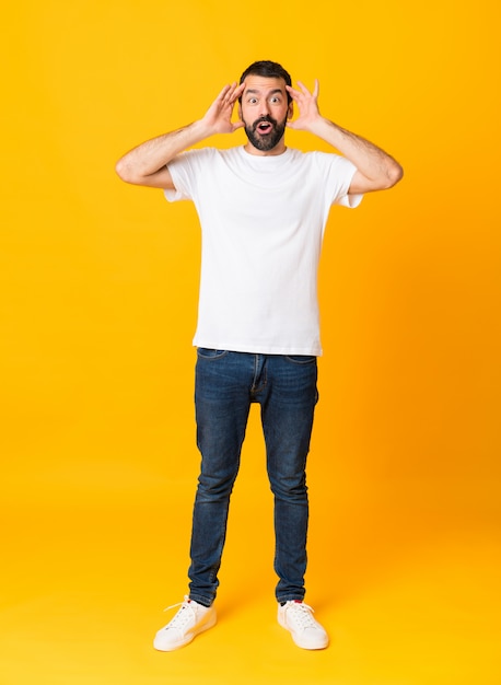 Tiro integral del hombre con barba sobre fondo amarillo aislado con expresión de sorpresa