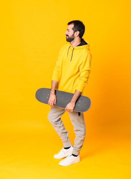 Tiro integral de un hombre skater sobre amarillo aislado