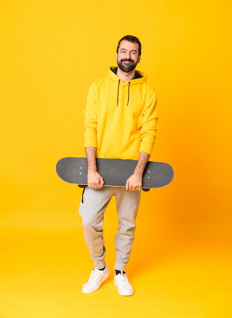Tiro integral de un hombre skater sobre pared amarilla aislada