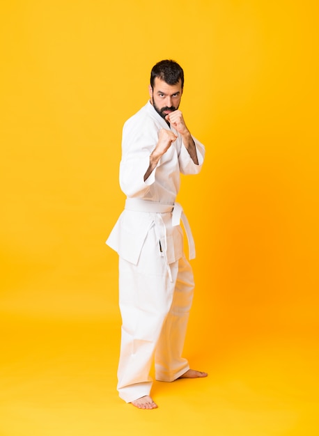 Tiro integral del hombre sobre amarillo aislado haciendo karate