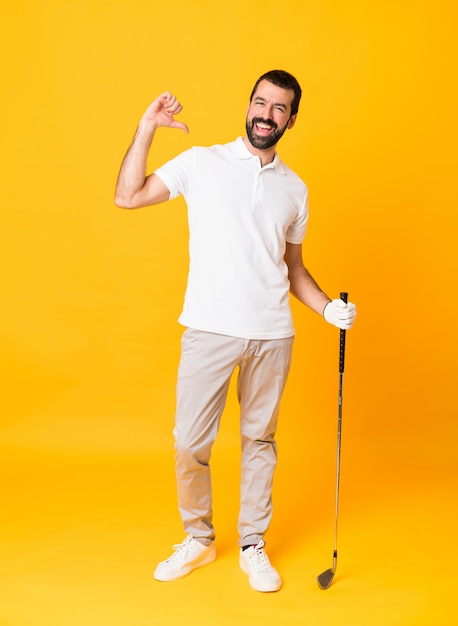 Tiro integral del hombre sobre amarillo aislado jugando al golf y orgulloso de sí mismo