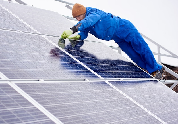 Tiro integral de un ingeniero profesional electricista trabajador instalando o reparando paneles solares en la planta de energía fotovoltaica copyspace reemplazo profesión ocupación trabajo renovable energía limpia.