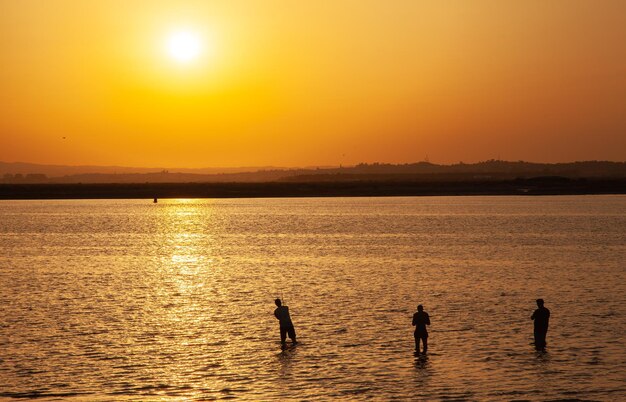 tiro largo de dos pescadores en una espectacular puesta de sol en una playa en el sur de España